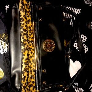 Black with gold tone hardware and faux leopard fur accents. Purse